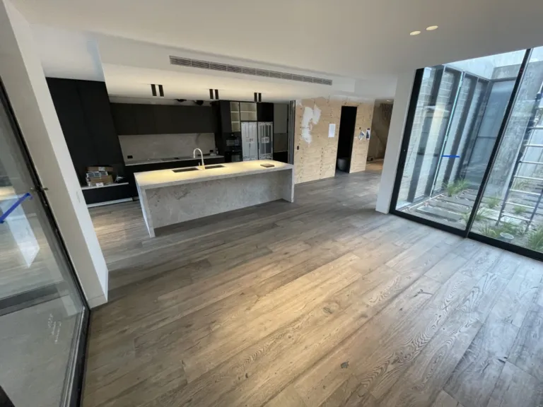 Annapolis Grey Oak wide boards in an open-plan kitchen with a dark island and glass courtyard