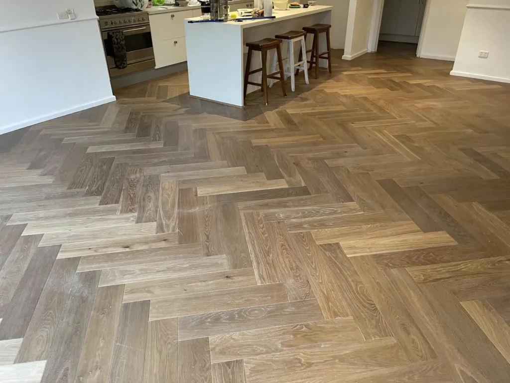 Sherbrooke Oak herringbone parquetry running through an open kitchen with a timber-topped island