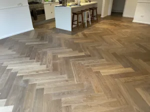Sherbrooke Oak herringbone parquetry running through an open kitchen with a timber-topped island
