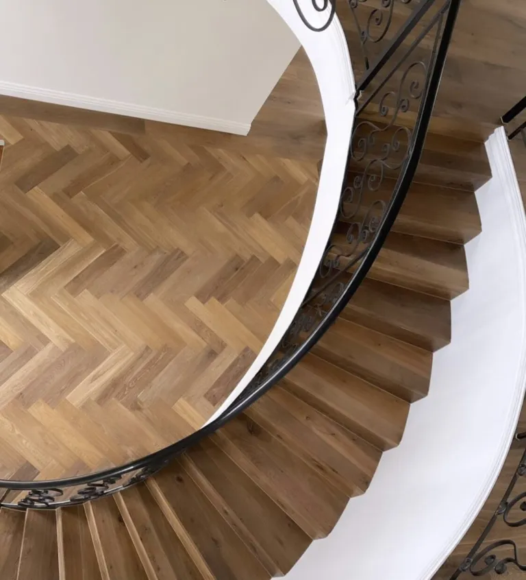 Herringbone landing at the top of a curved oak staircase