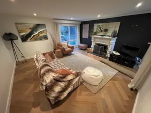Sherbrooke Oak herringbone parquetry in a lounge with a white fireplace and dark feature wall