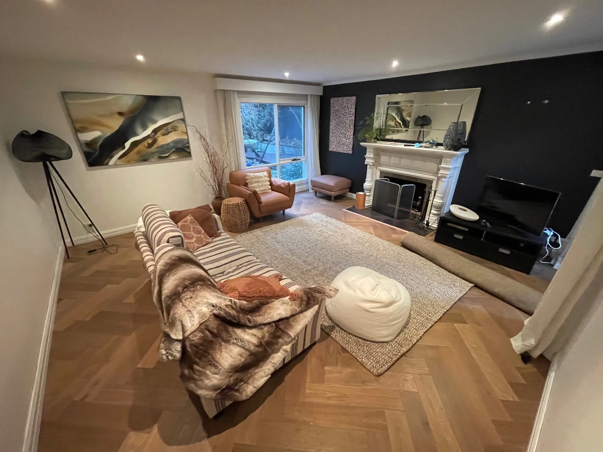 Sherbrooke Oak herringbone parquetry in a lounge with a white fireplace and dark feature wall