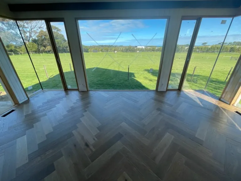 Herringbone oak floor in a glass-walled room looking out to open paddocks