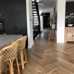 Oak herringbone in a black kitchen with rattan stools