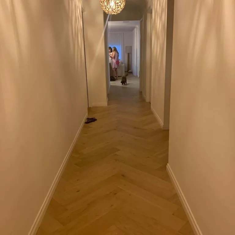Oak herringbone parquetry down a warm, narrow hallway
